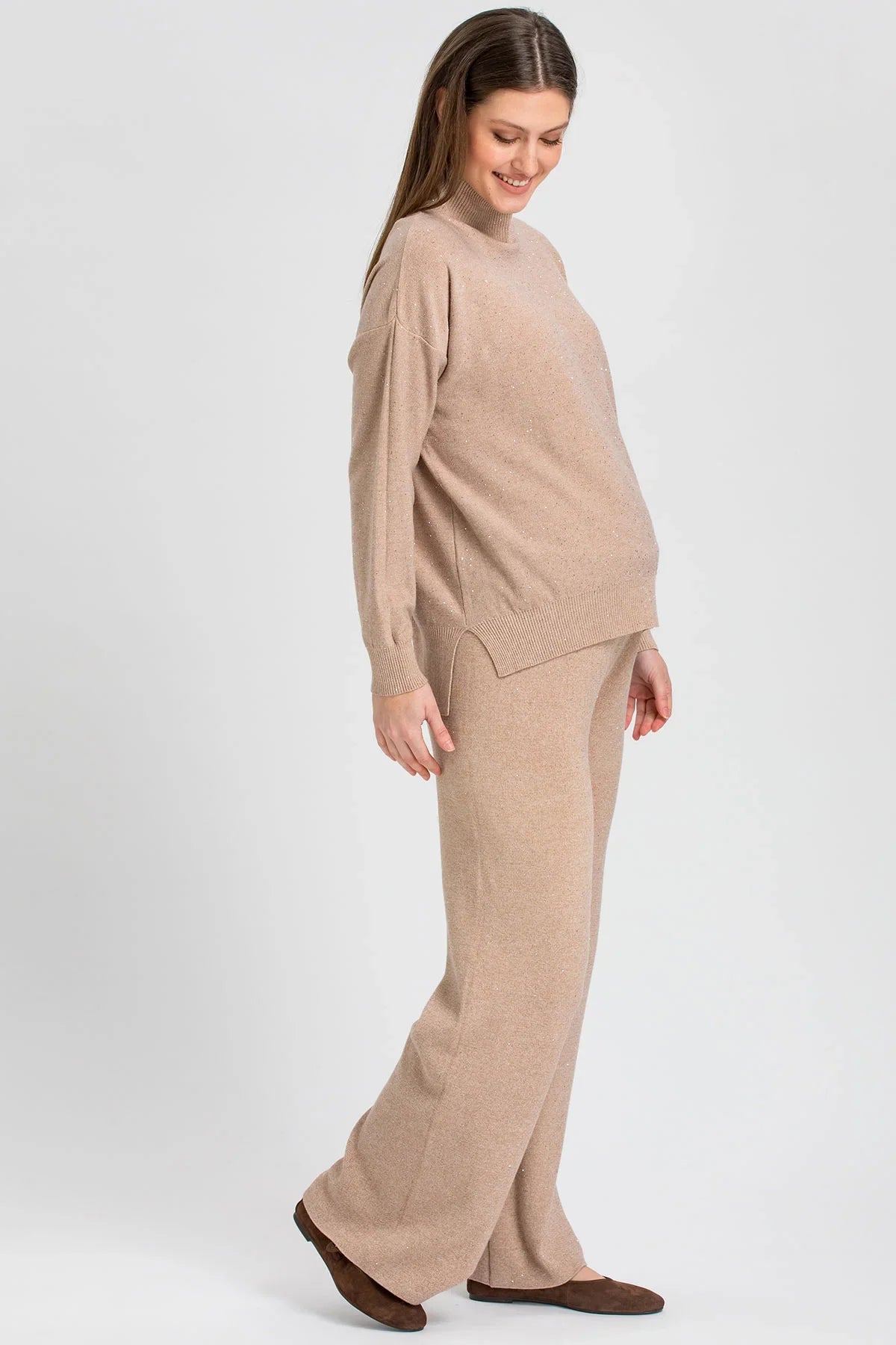 Beige maternity sweater with a high neck and wide-leg maternity pants with shimmering details in a soft knit.