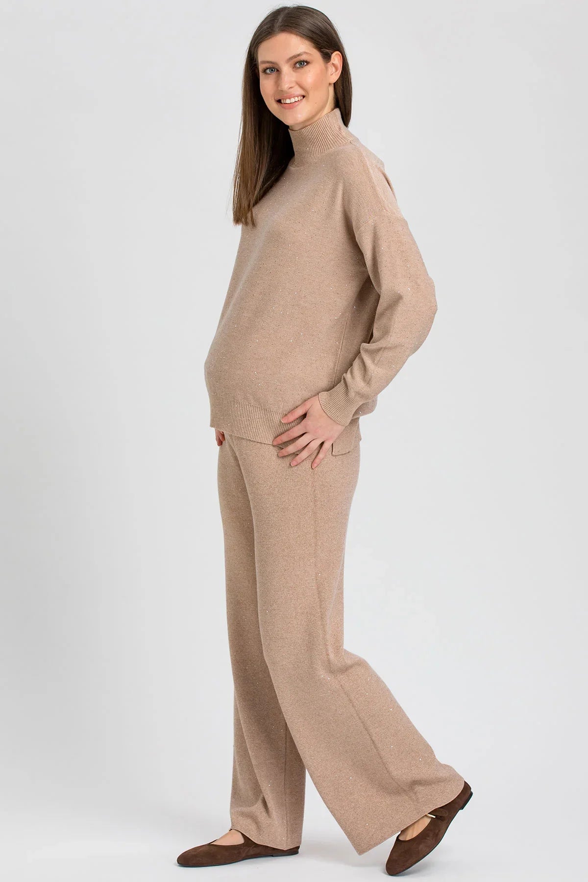 Beige maternity sweater with a high neck and wide-leg maternity pants with shimmering details in a soft knit.