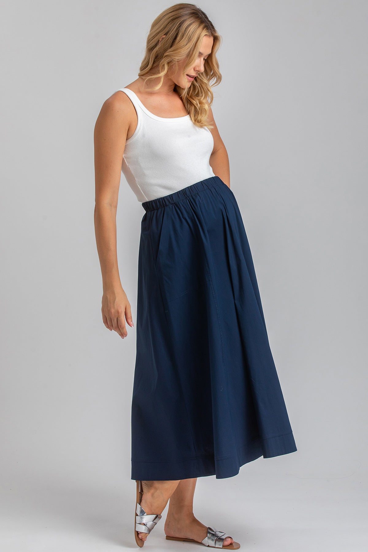Donna con gonna premaman blu a vita alta e top bianco, abbigliamento premaman elegante
