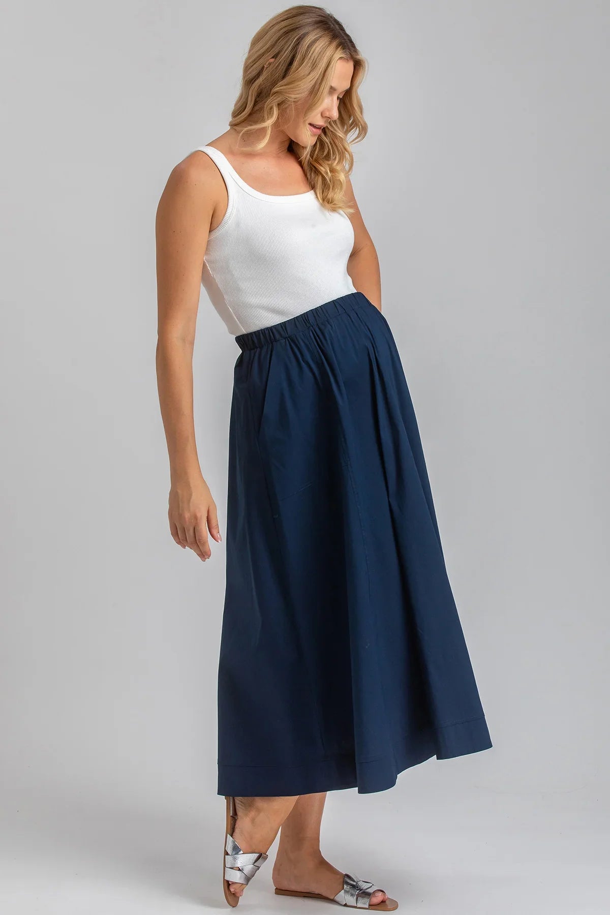 Donna con gonna premaman blu a vita alta e top bianco, abbigliamento premaman elegante