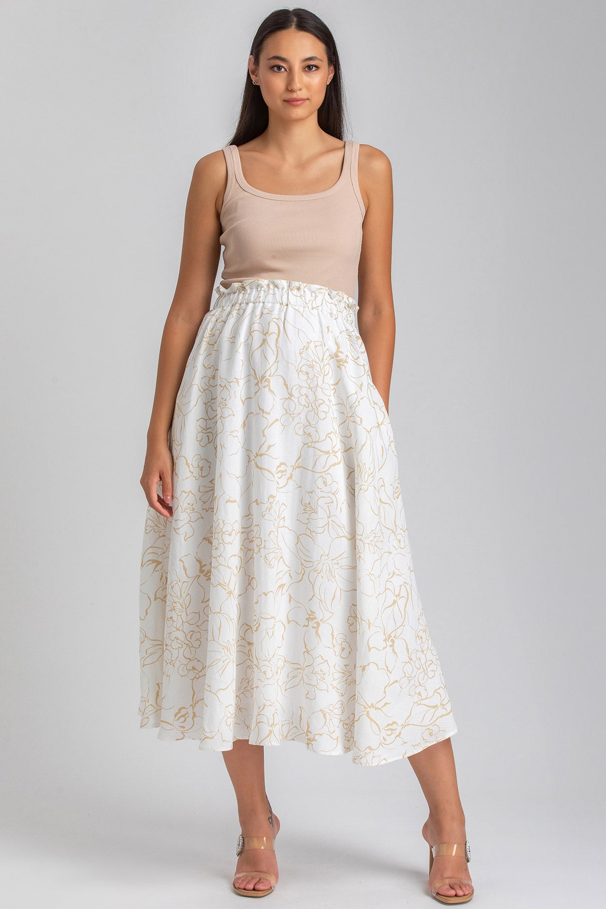 Donna con top beige e gonna ampia bianca a fiori, abbigliamento premaman elegante