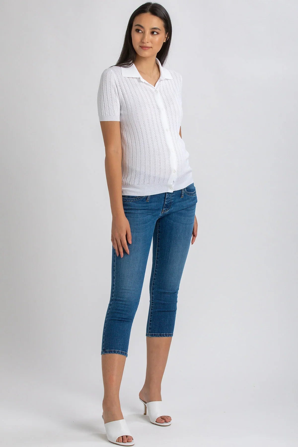 Donna incinta con camicia bianca e jeans premaman skinny blu Capri, sandali bianchi