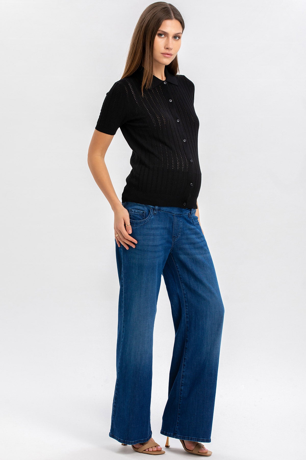 Donna incinta con maglia premaman nera e jeans larghi, moda comoda gravidanza