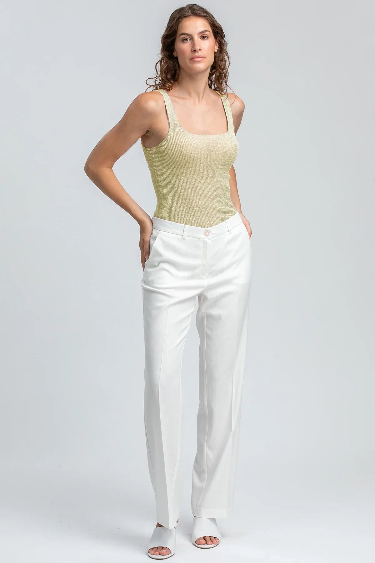Modella con pantaloni premaman bianchi eleganti e top senza maniche, abbigliamento premaman.