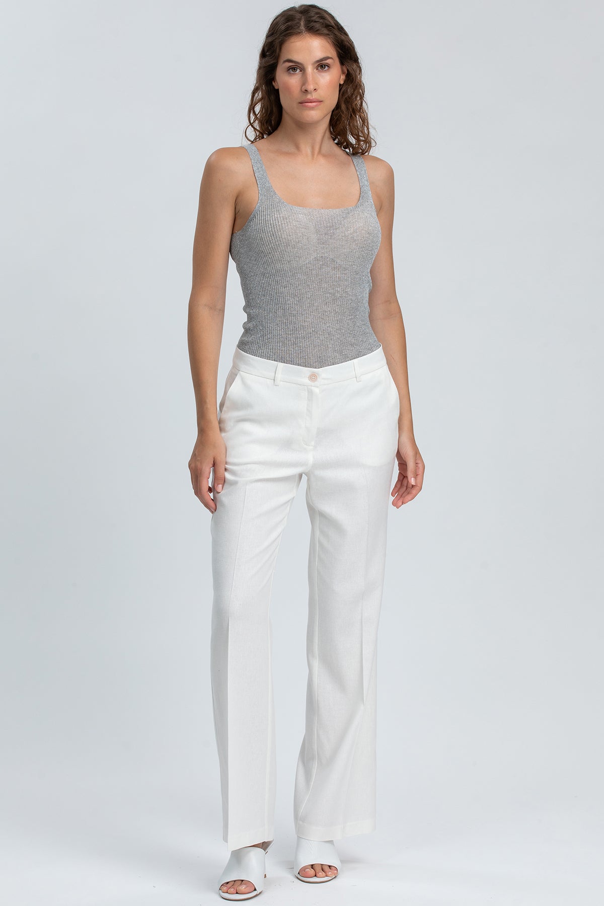 Pantaloni premaman eleganti bianchi da donna, indossati con top grigio smanicato