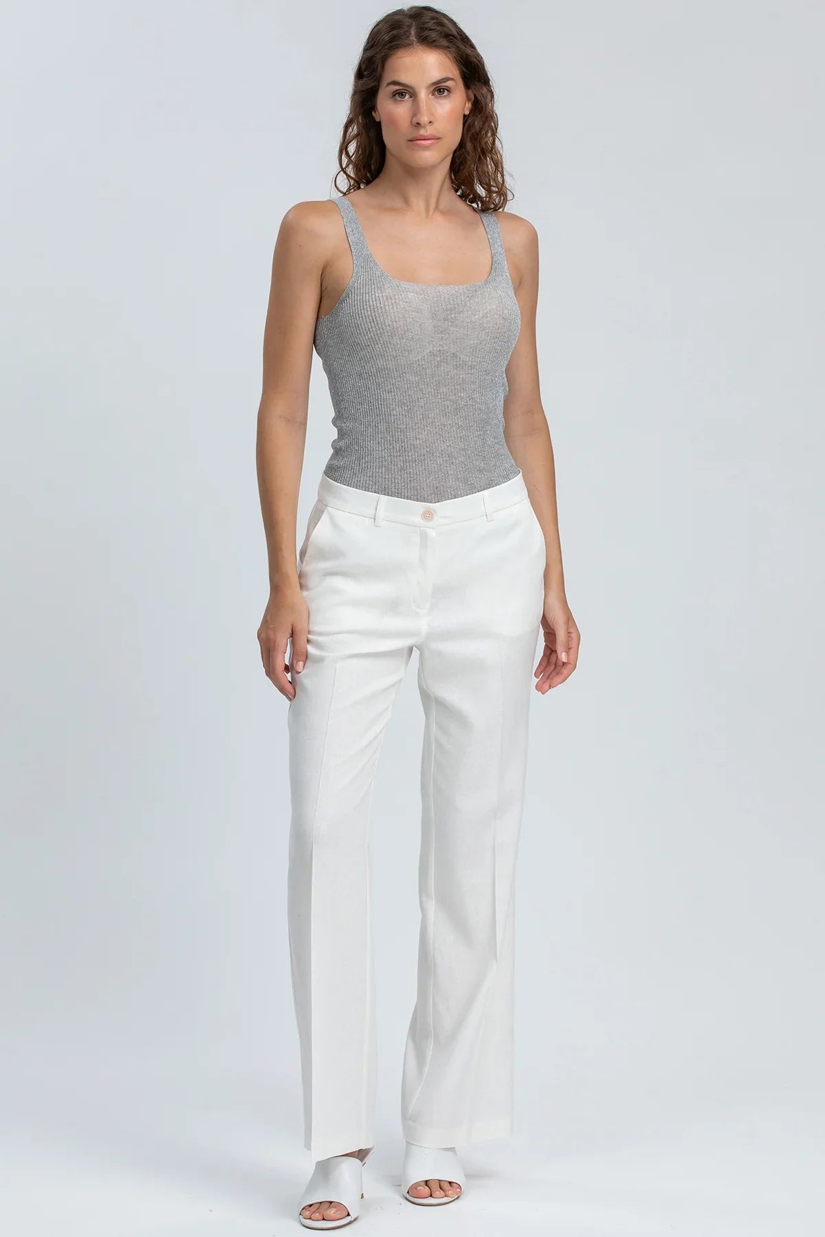 Pantaloni premaman eleganti bianchi da donna, indossati con top grigio smanicato