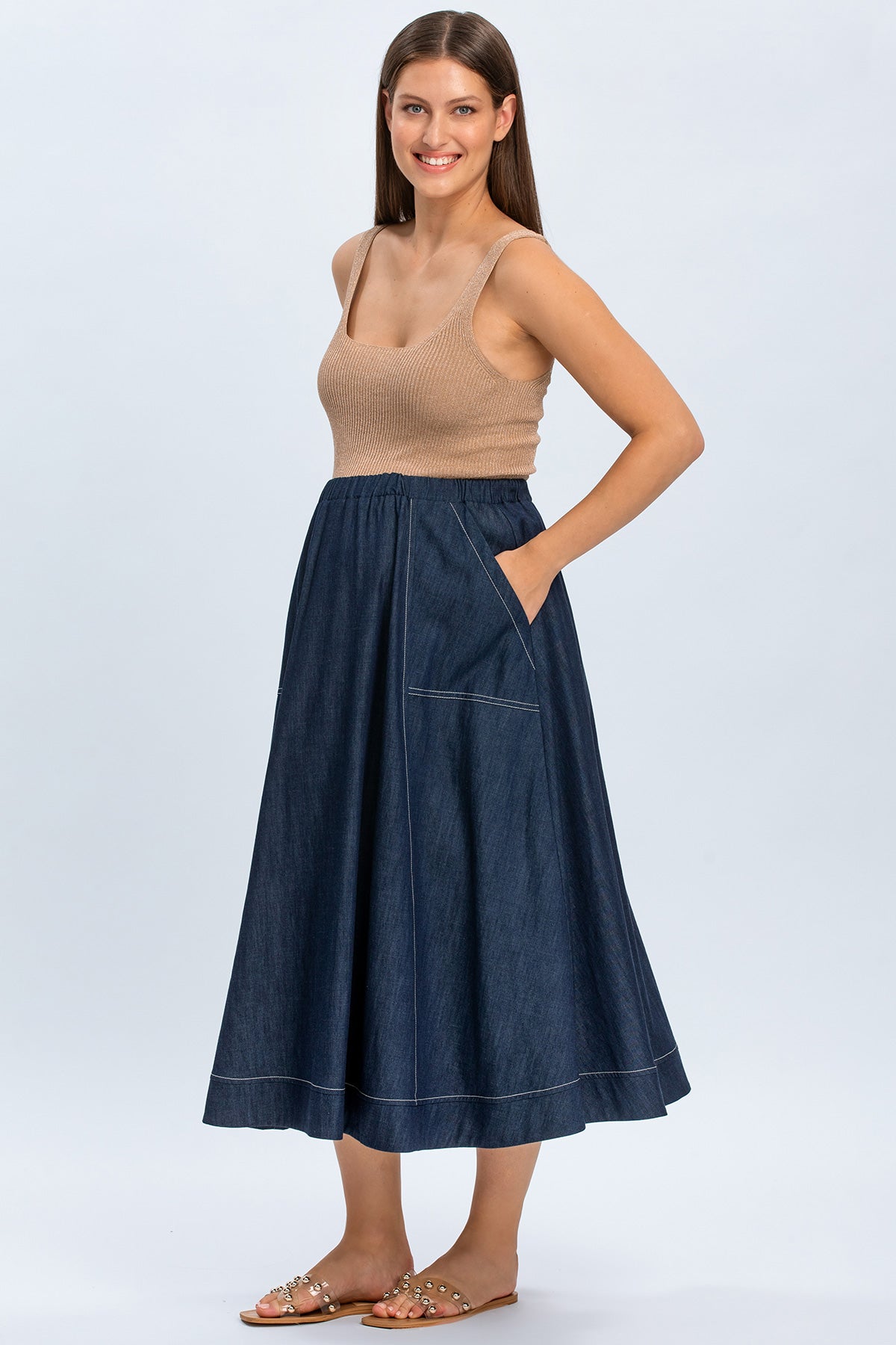 Donna con gonna lunga premaman in jeans e top beige, abbigliamento premaman elegante