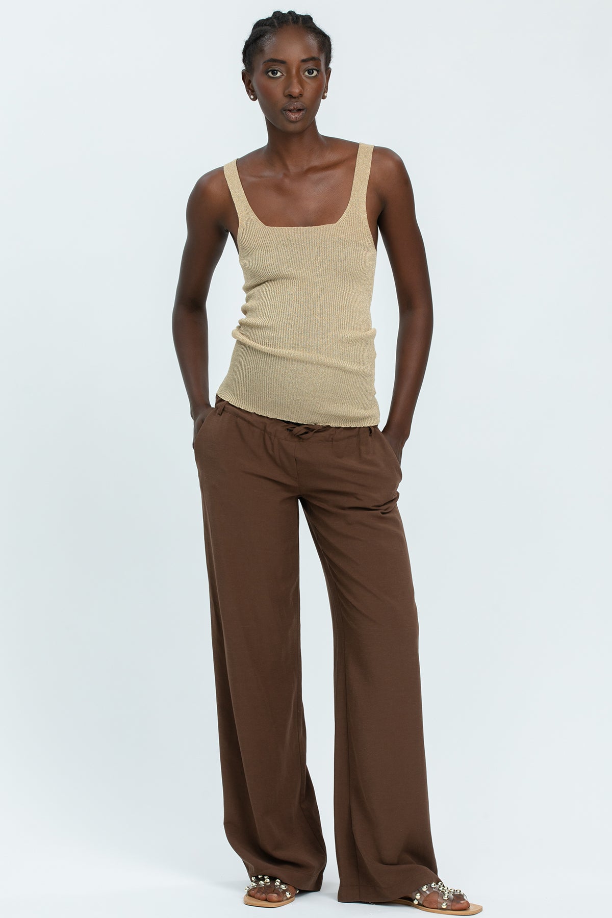 Donna con pantaloni premaman marroni larghi e top beige, abbigliamento premaman elegante