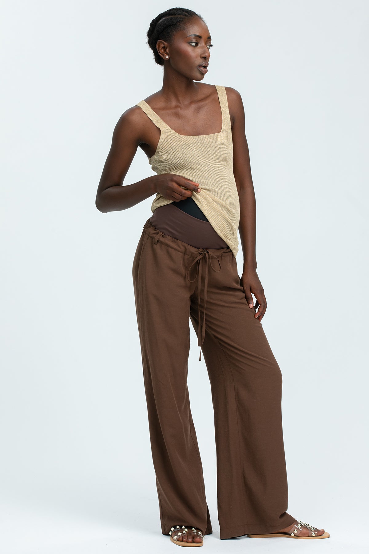 Pantaloni premaman marroni a vita alta con fascia elastica per gravidanza, indossati da donna