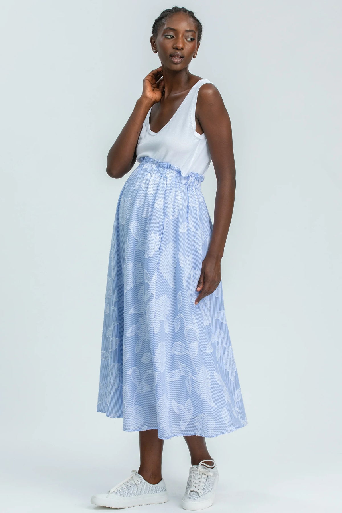 Modella indossa una gonna premaman azzurra lunga con fantasia floreale, look premaman elegante.