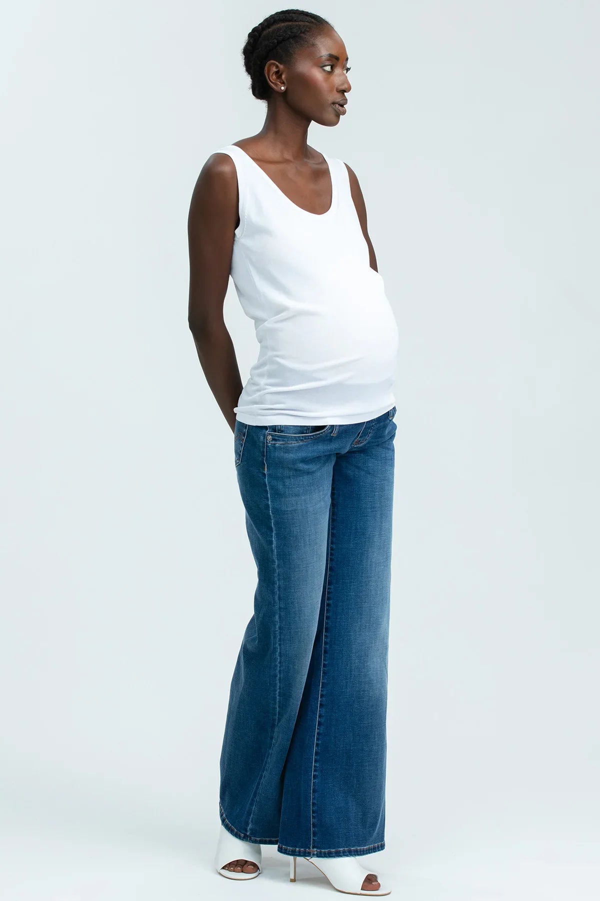Donna incinta con top bianco e jeans premaman larghi, abbigliamento premaman elegante