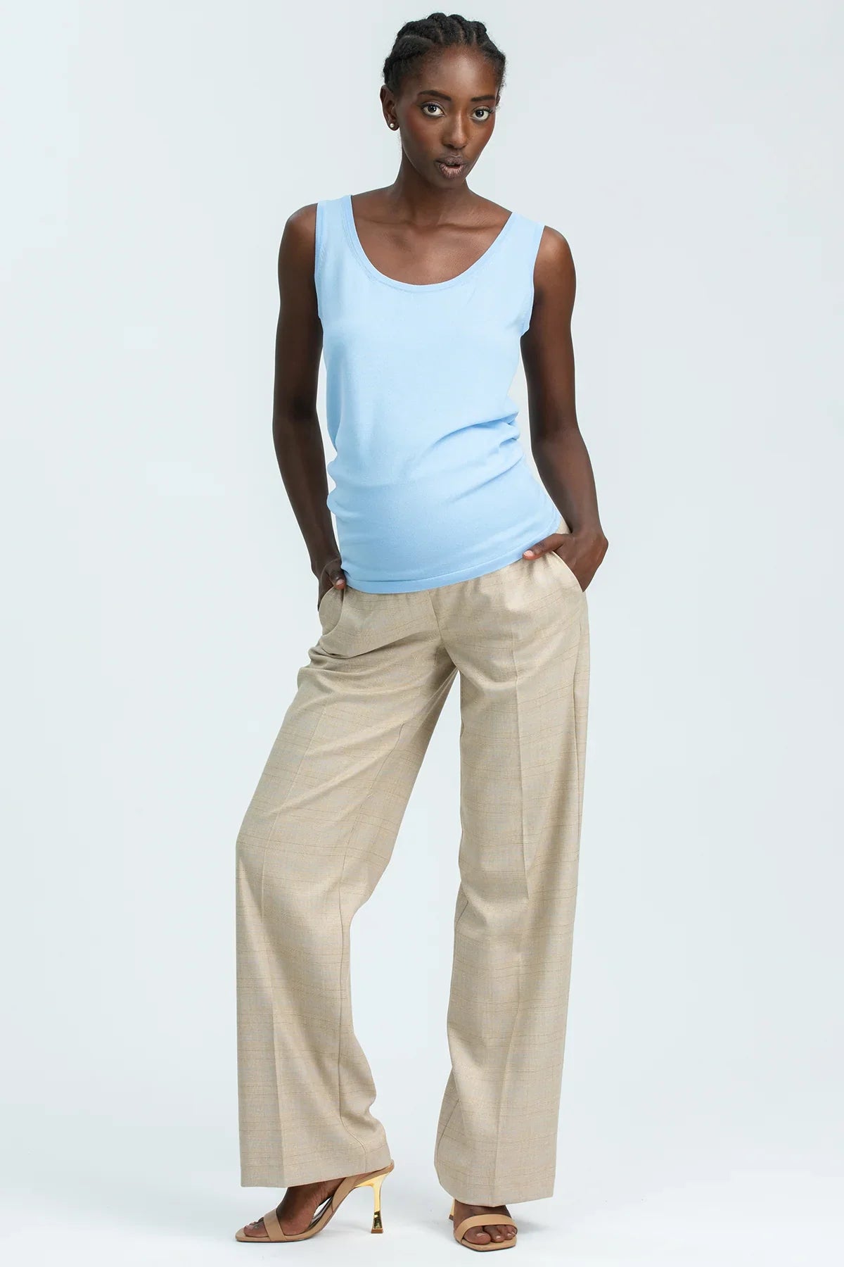 Modella indossa pantaloni premaman beige e top celeste, abbigliamento premaman elegante.