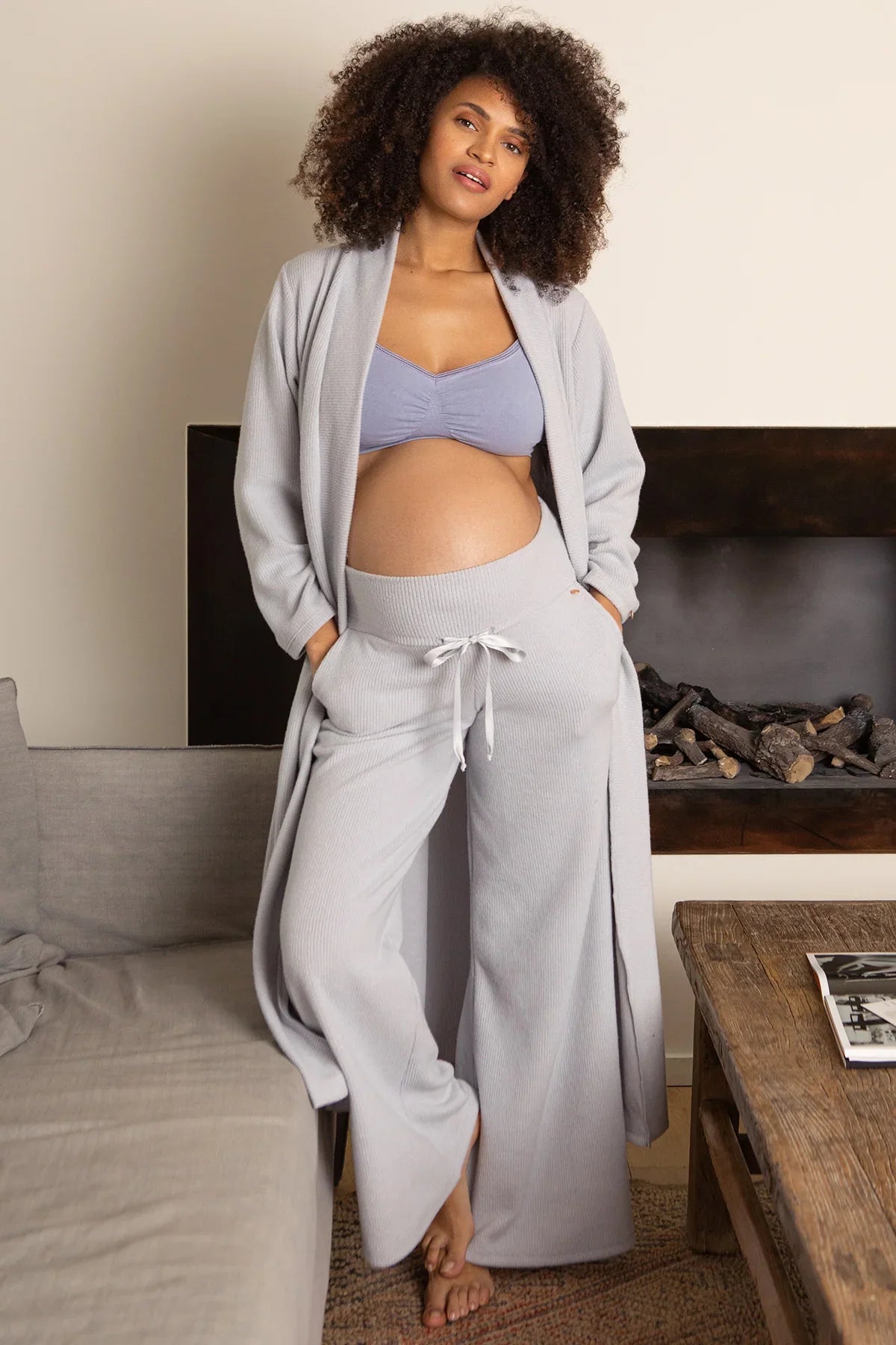 Donna incinta con pantaloni e cardigan premaman in maglia chiara, abbigliamento premaman elegante.