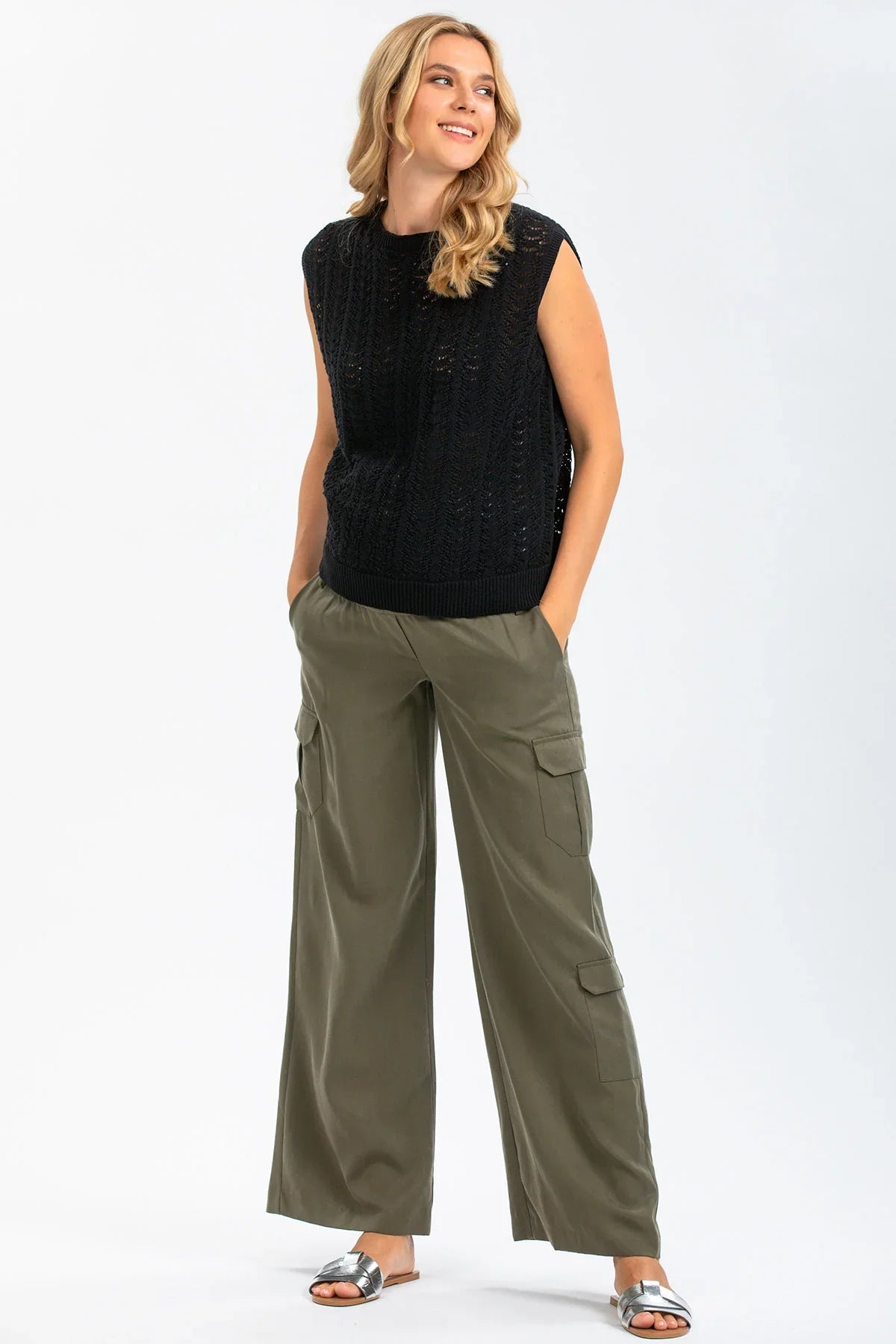 Donna con maglia nera traforata senza maniche e pantaloni cargo premaman verde oliva