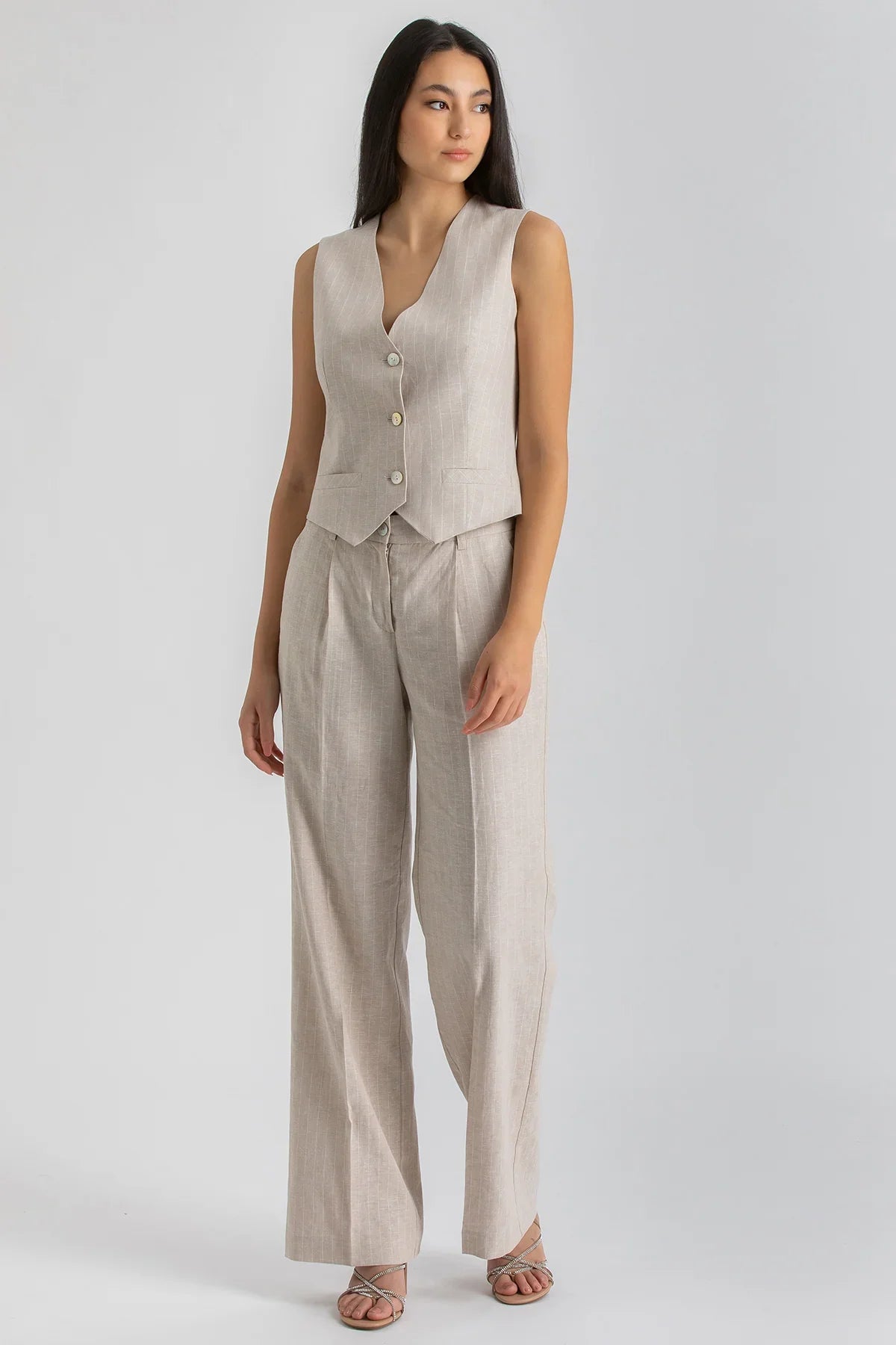 Completo premaman donna con gilet smanicato e pantaloni beige ampi in tessuto leggero.