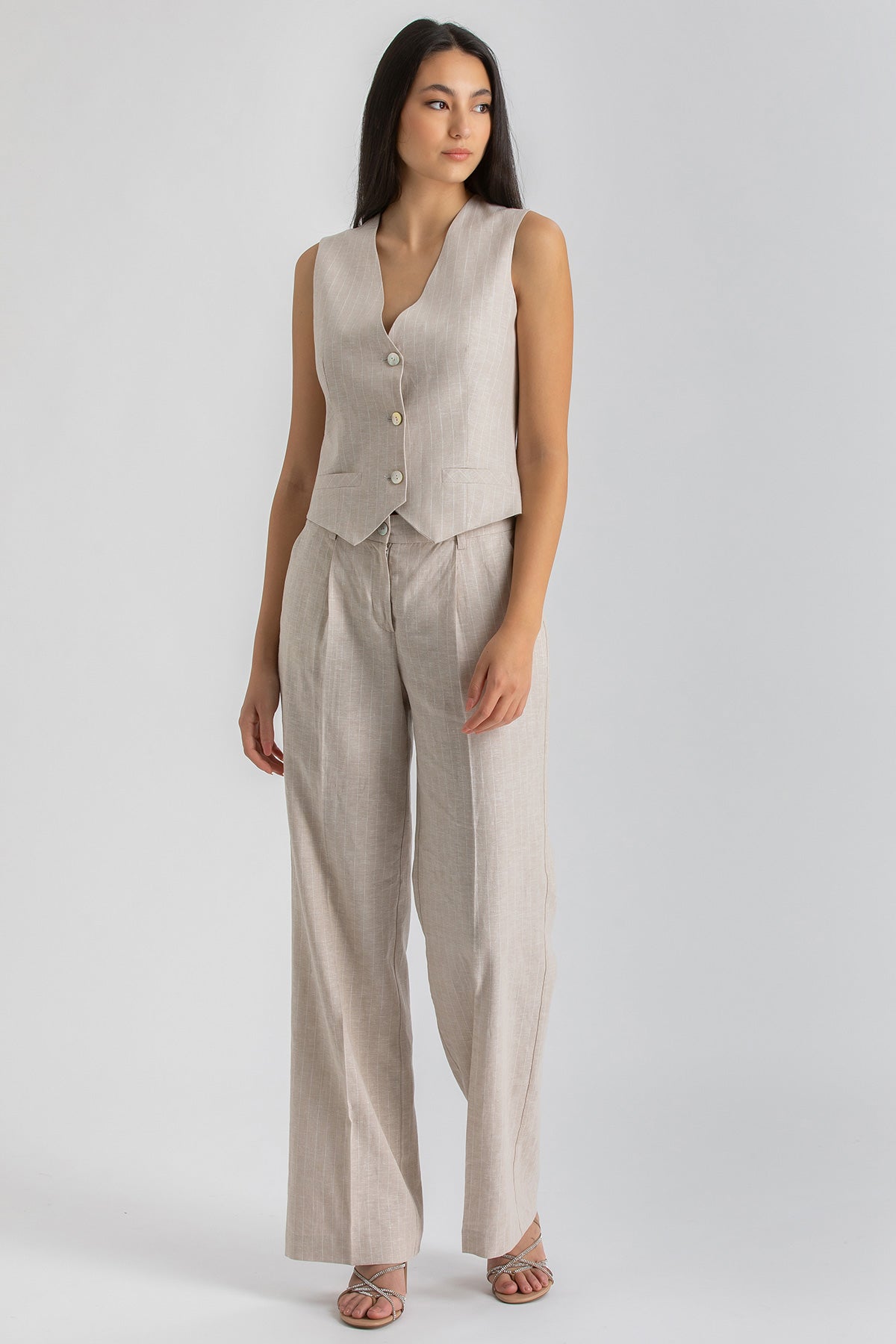 Completo premaman donna con gilet smanicato e pantaloni beige ampi in tessuto leggero.
