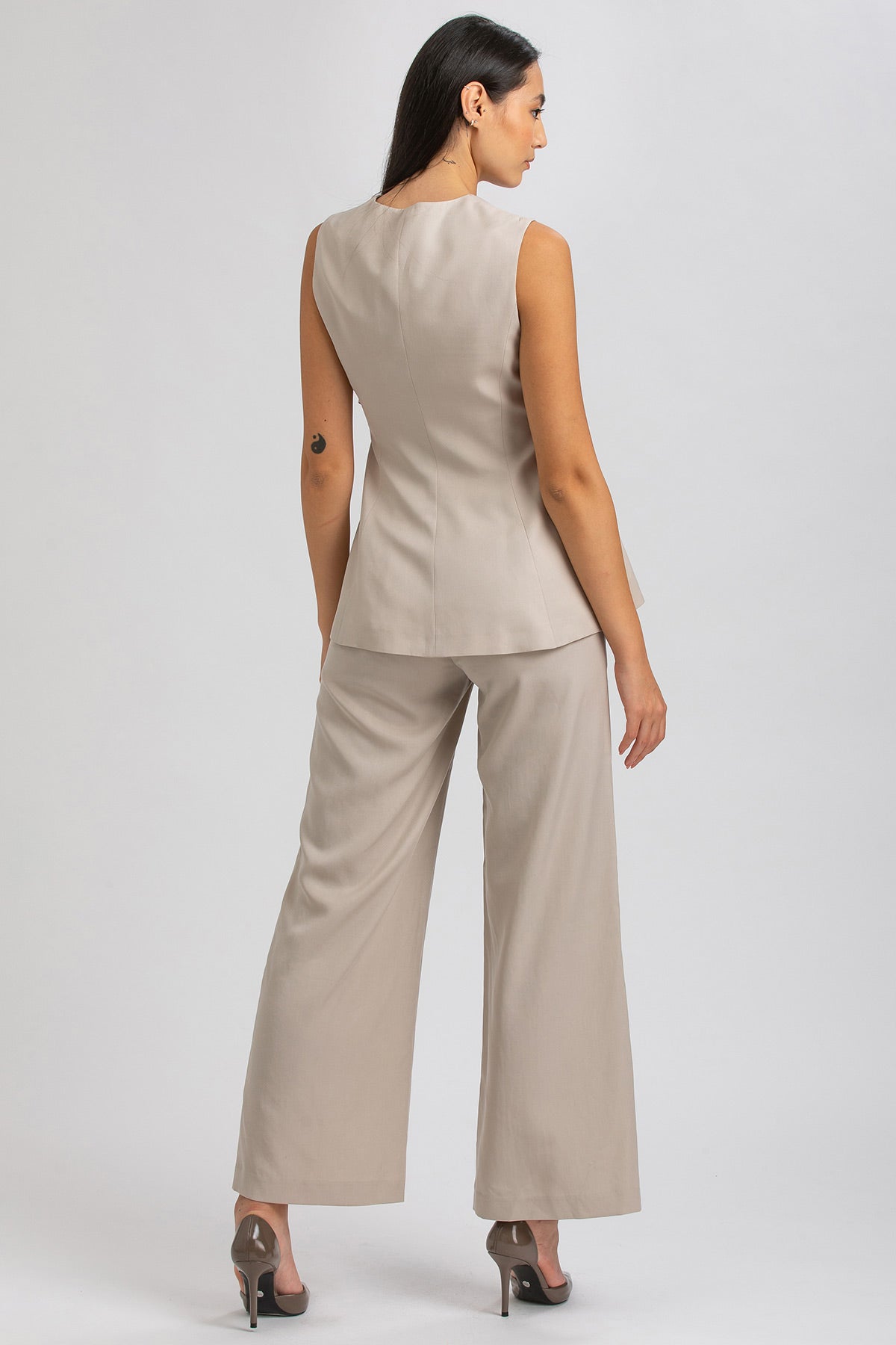 Completo premaman elegante beige, giacca smanicata e pantaloni larghi, donna di spalle