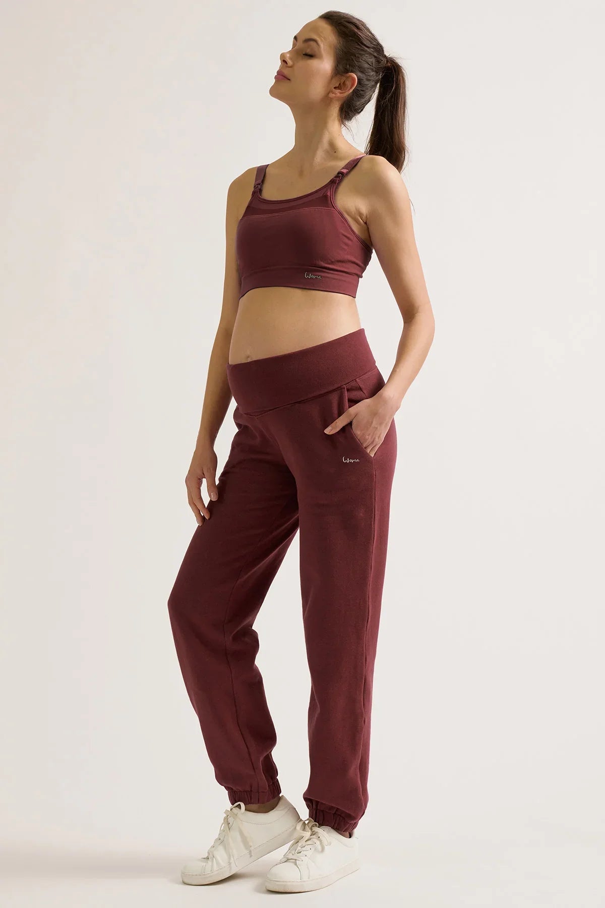 Donna che indossa pantaloni jogger premaman prugna e top coordinato Cache Coeur.