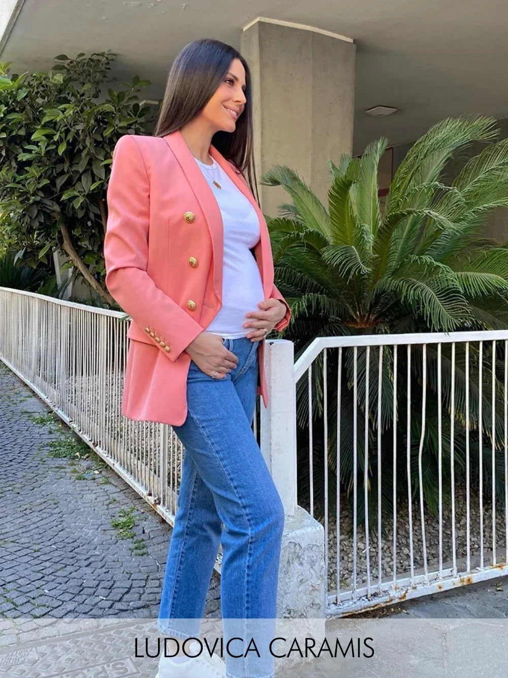 Donna con blazer corallo, t-shirt bianca e jeans premaman blu.