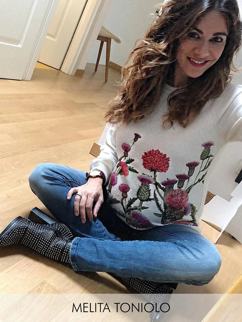 Donna con maglione premaman bianco ricamato con fiori e jeans premaman blu.