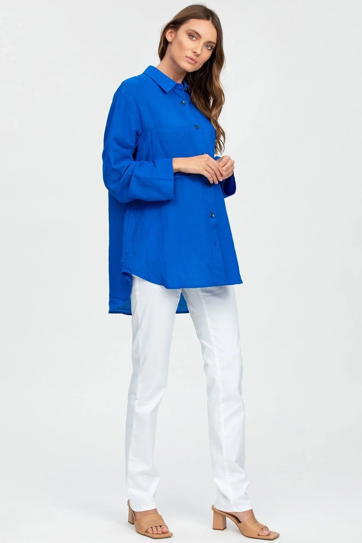Donna con camicia premaman blu lunga e pantaloni bianchi, abbigliamento gravidanza elegante.