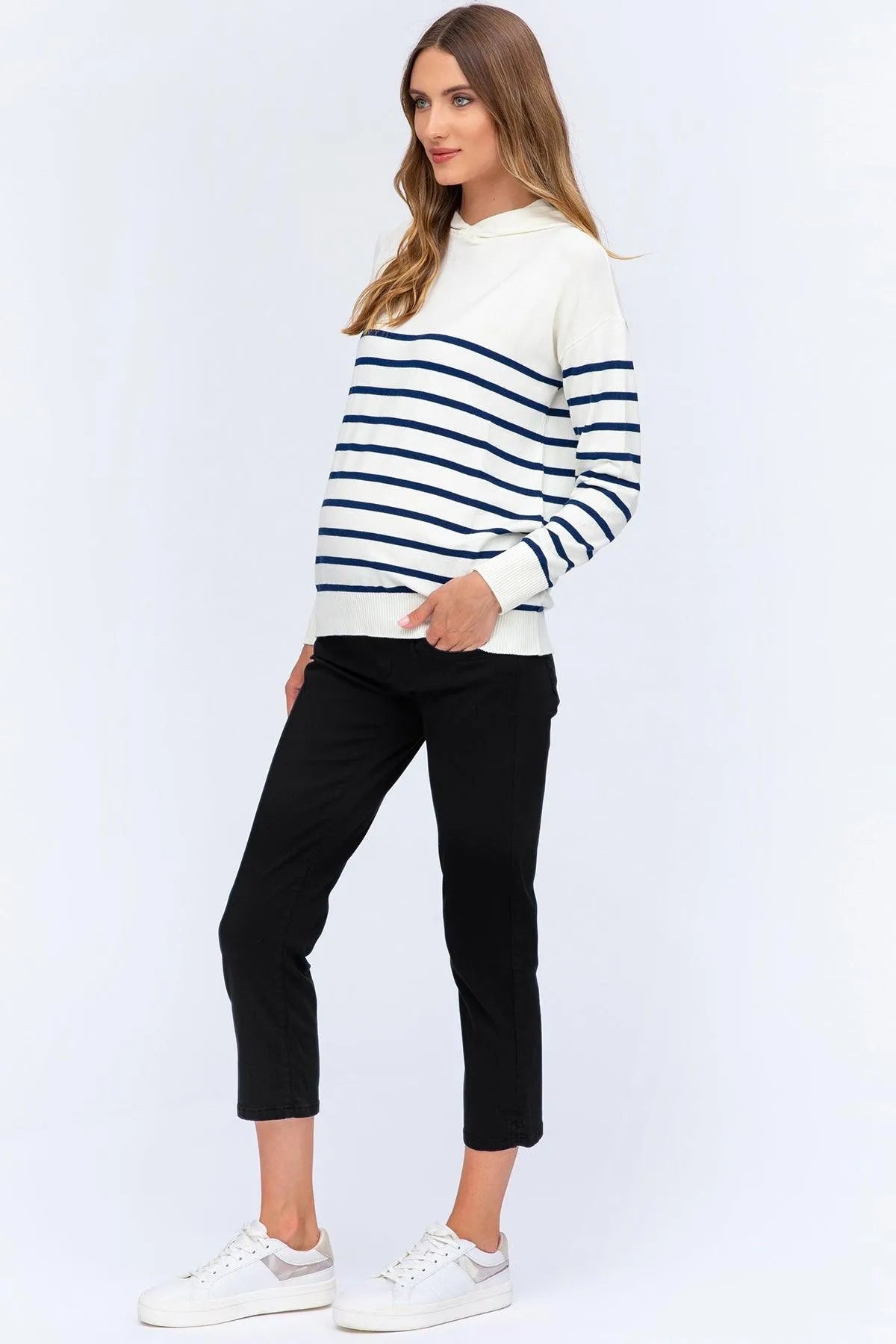 Modella che indossa maglione premaman bianco a righe blu e pantaloni neri cropped