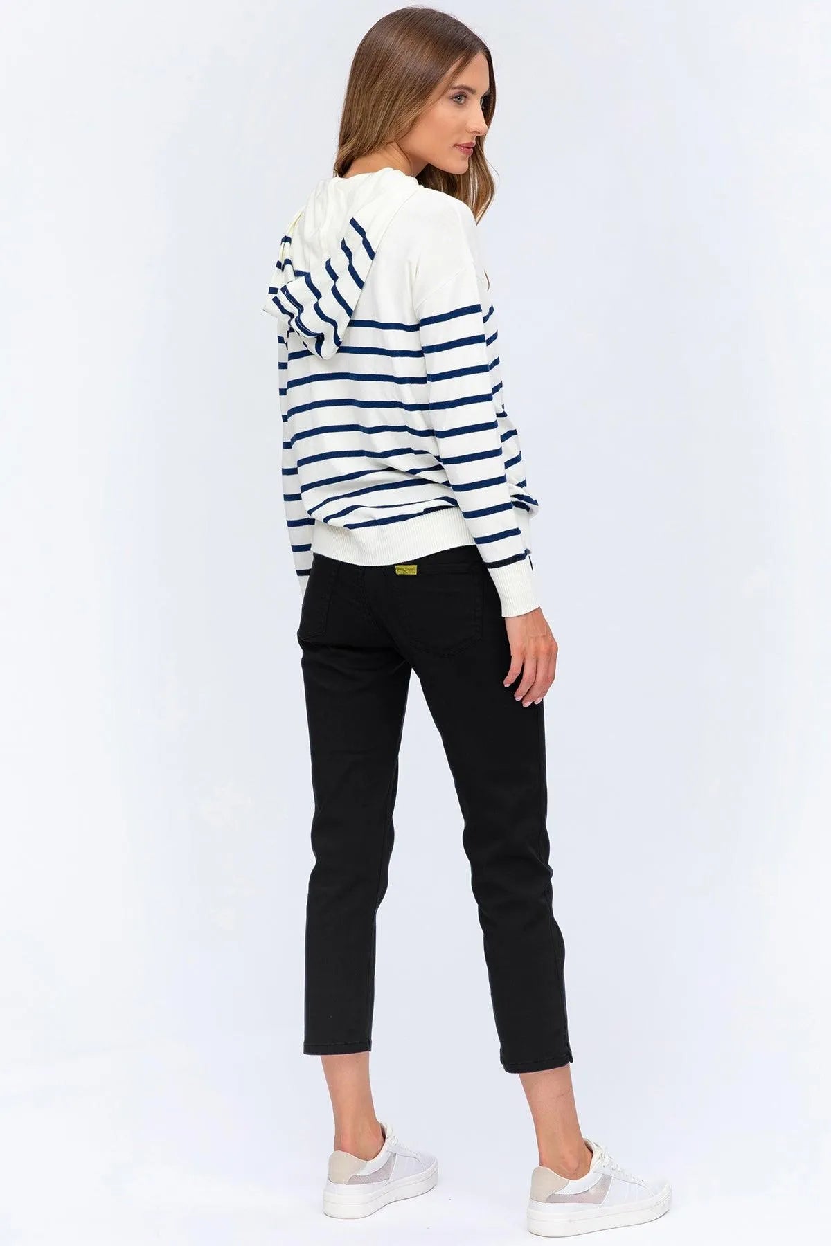 Donna con felpa premaman a righe bianche e blu, jeans neri, sneakers bianche