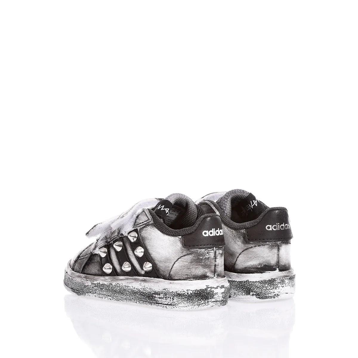Scarpe sportive nere e argento con borchie, moda urban casual premaman, fondo bianco.
