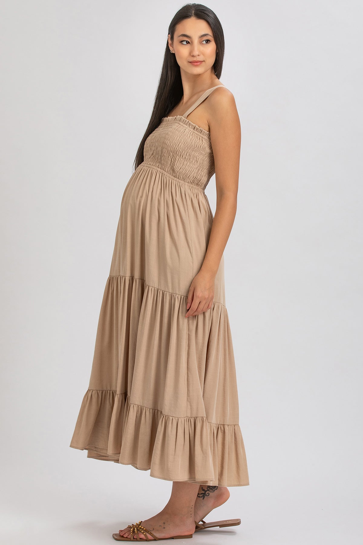 Donna incinta con abito premaman beige lungo senza maniche, vestito maternità elegante