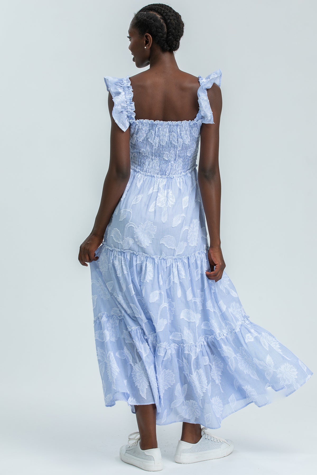 Abito premaman lungo azzurro con balze e fantasia floreale, vestibilità comoda ed elegante.