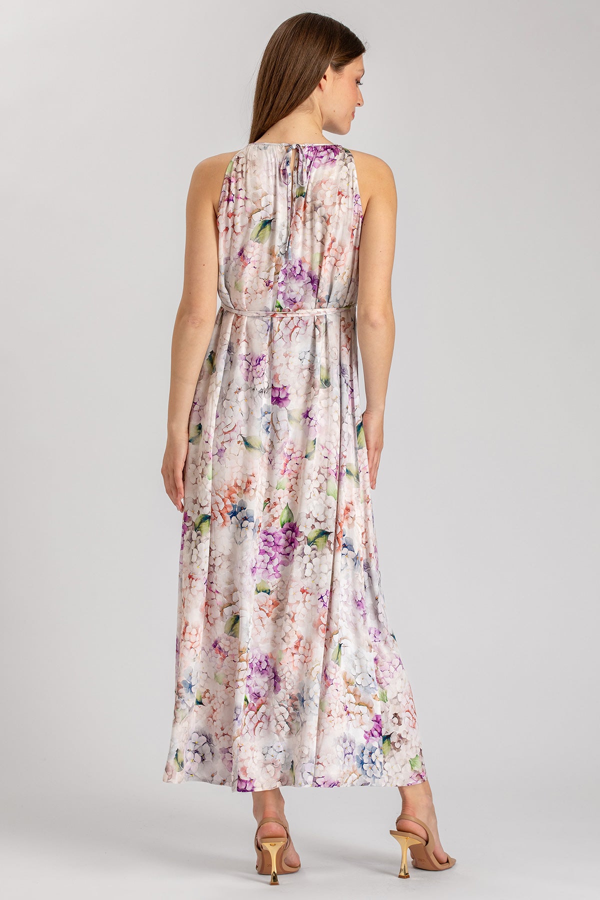 Vestito premaman lungo floreale elegante, donna di spalle, tessuto leggero e colorato.
