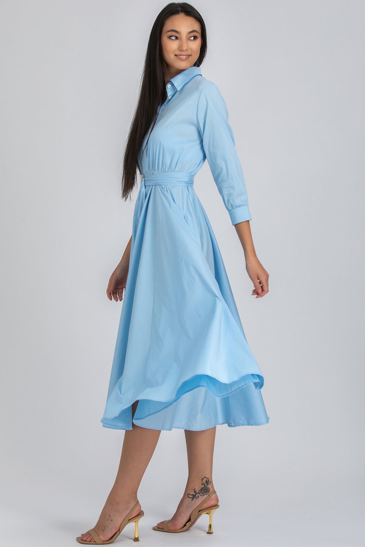 Donna con abito premaman azzurro a maniche lunghe e gonna svasata, sandali beige
