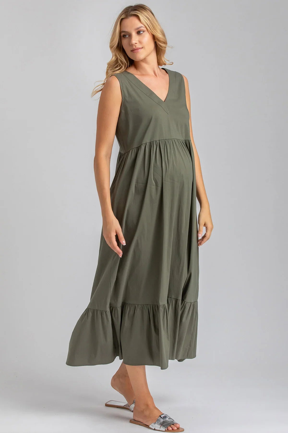 Modella indossa abito premaman verde senza maniche, con scollo a V e gonna ampia.