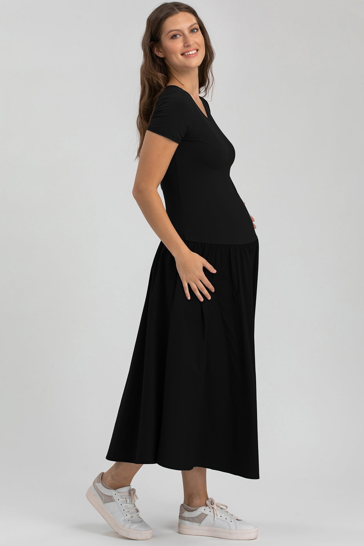 Abito premaman nero a maniche corte, lungo, elegante e confortevole, indossato da donna incinta.