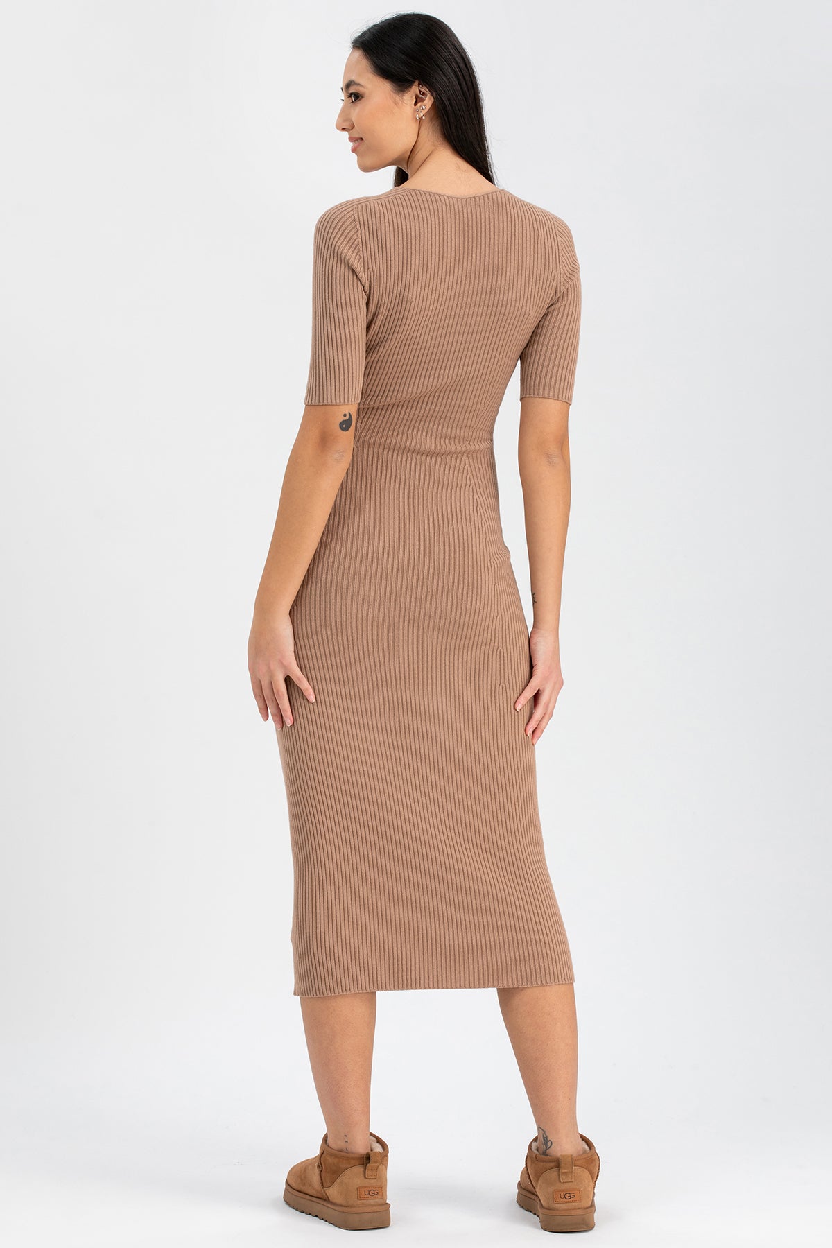 Donna di profilo con abito premaman beige a costine, maniche corte, su sfondo chiaro.
