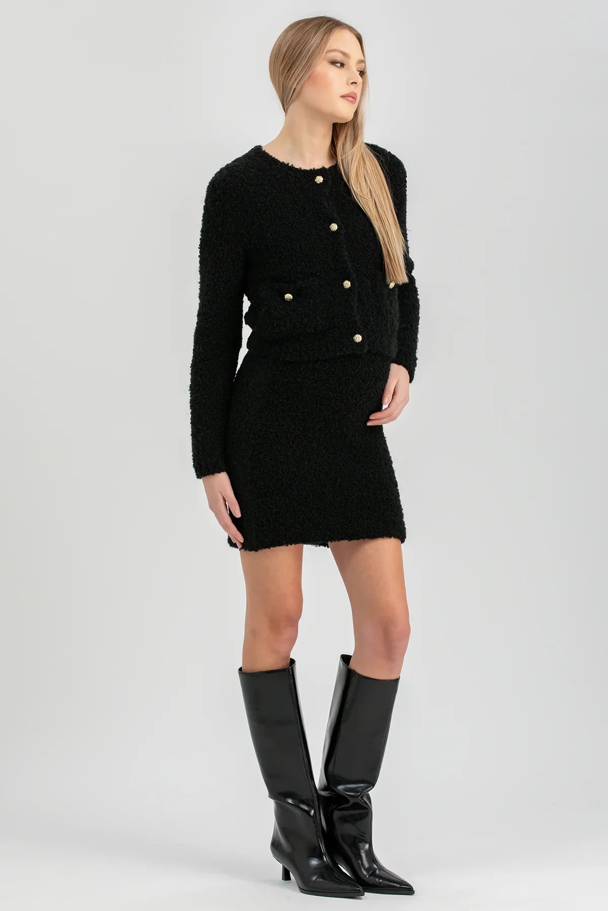 Modella indossa completo premaman elegante nero con giacca e minigonna, stivali alti neri