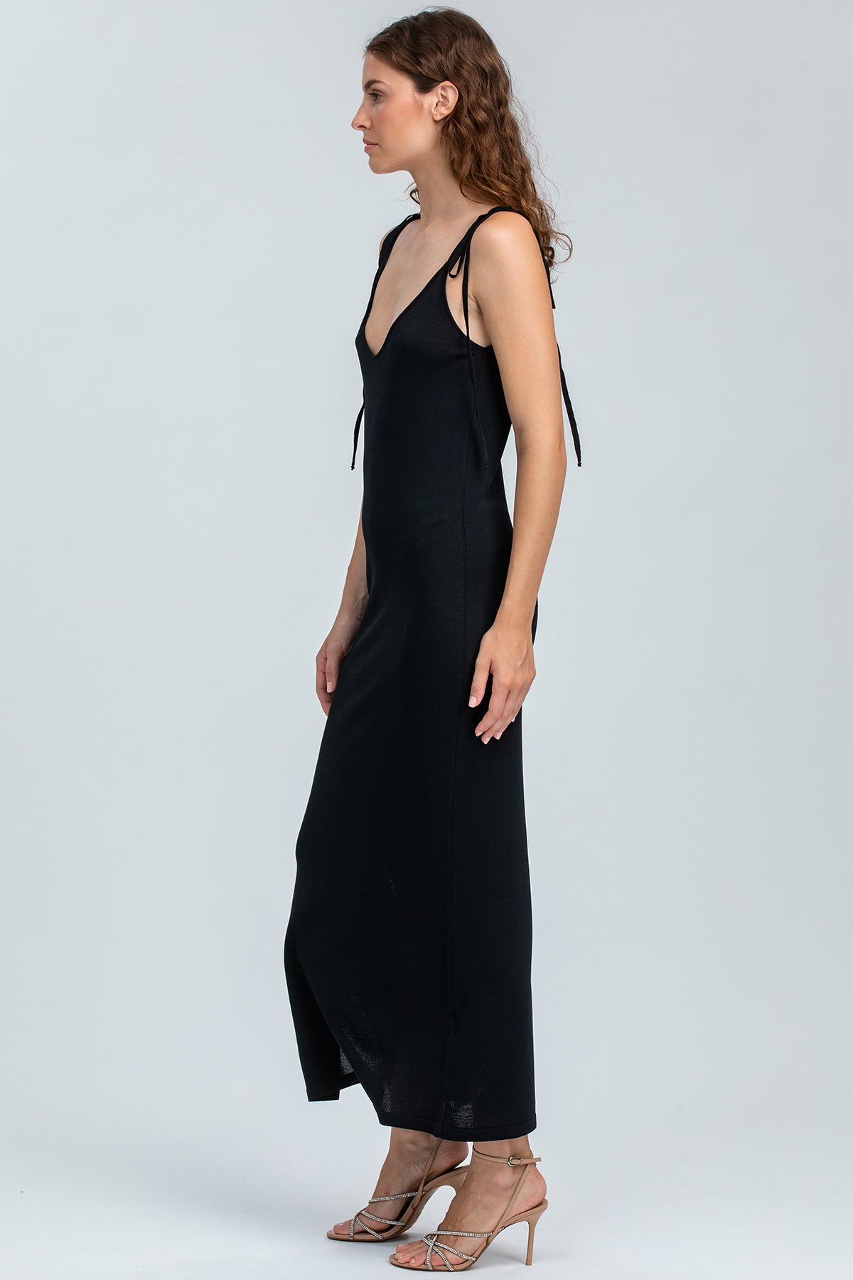 Abito premaman nero lungo con spalline sottili, elegante, indossato da donna in piedi