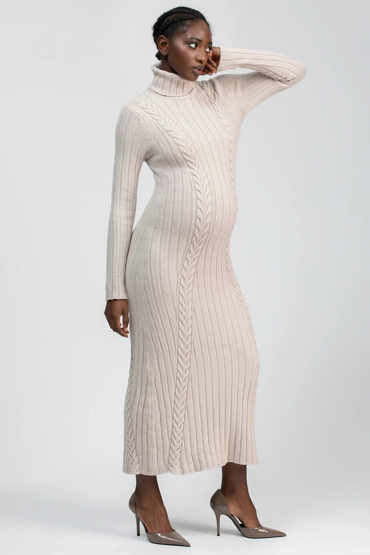Abito premaman in maglia beige con lavorazione treccia, collo alto e maniche lunghe.