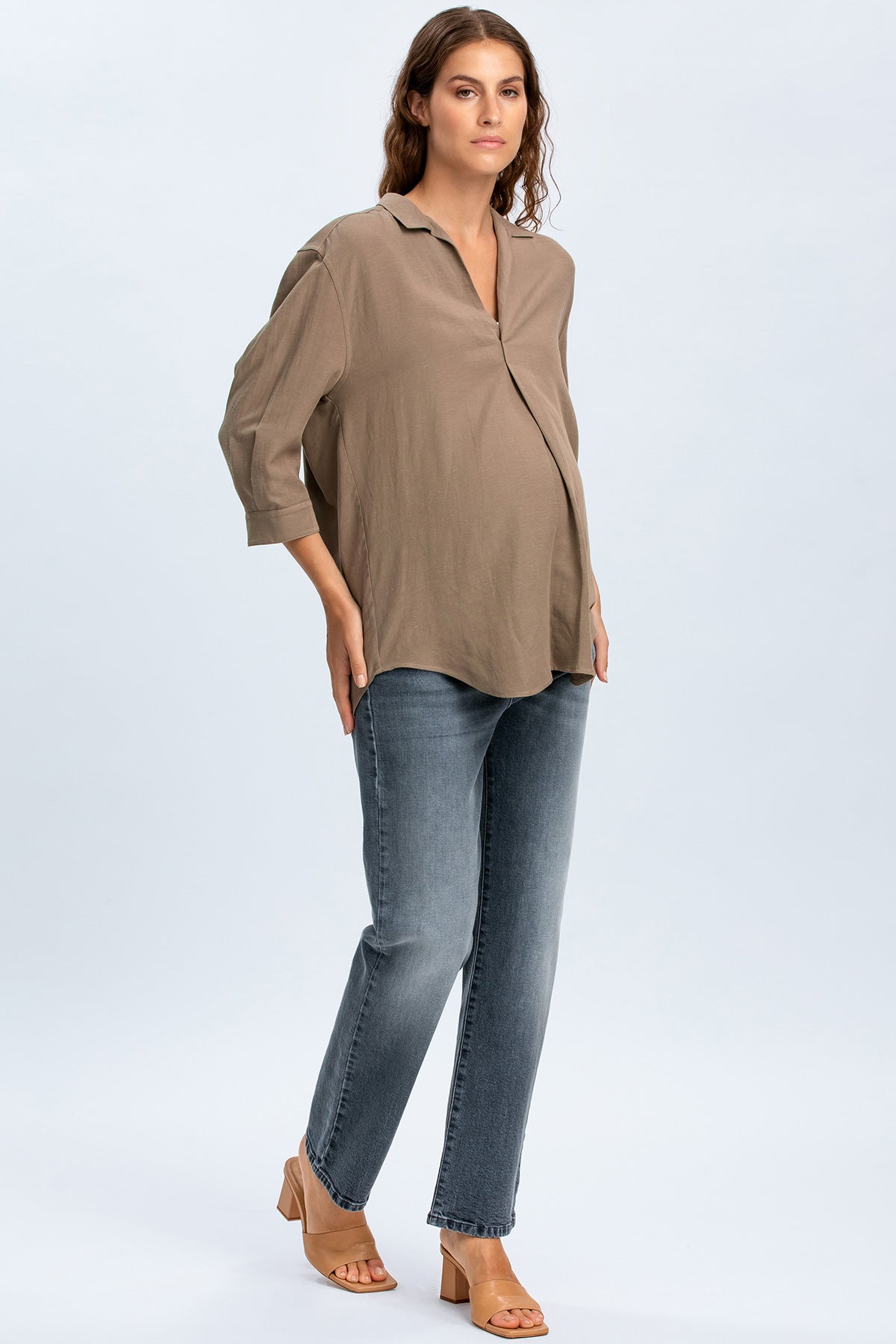 Modella indossa camicia premaman beige e jeans premaman dritti, look casual elegante
