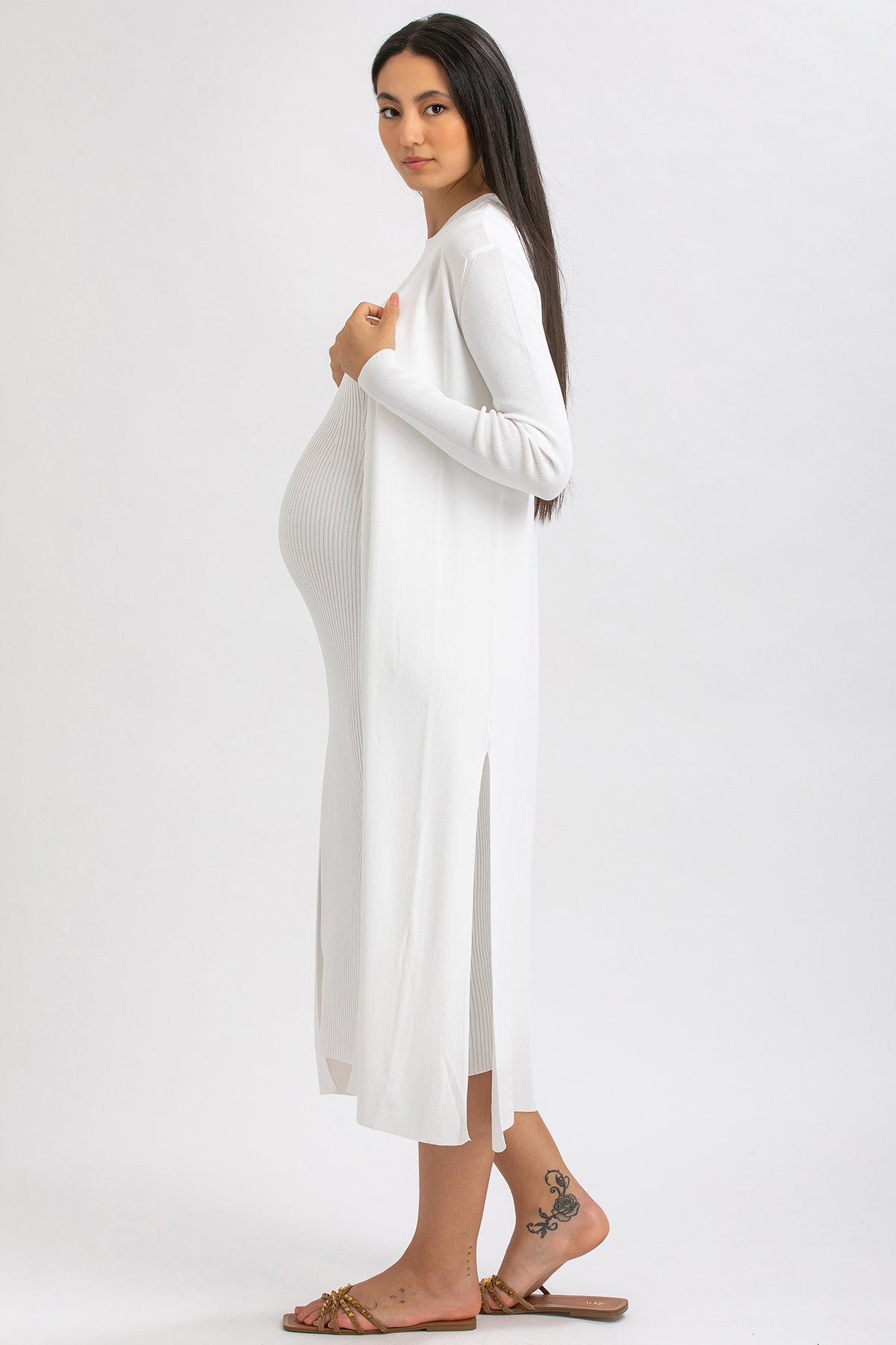 Donna incinta con abito premaman bianco elegante e lungo su sfondo neutro