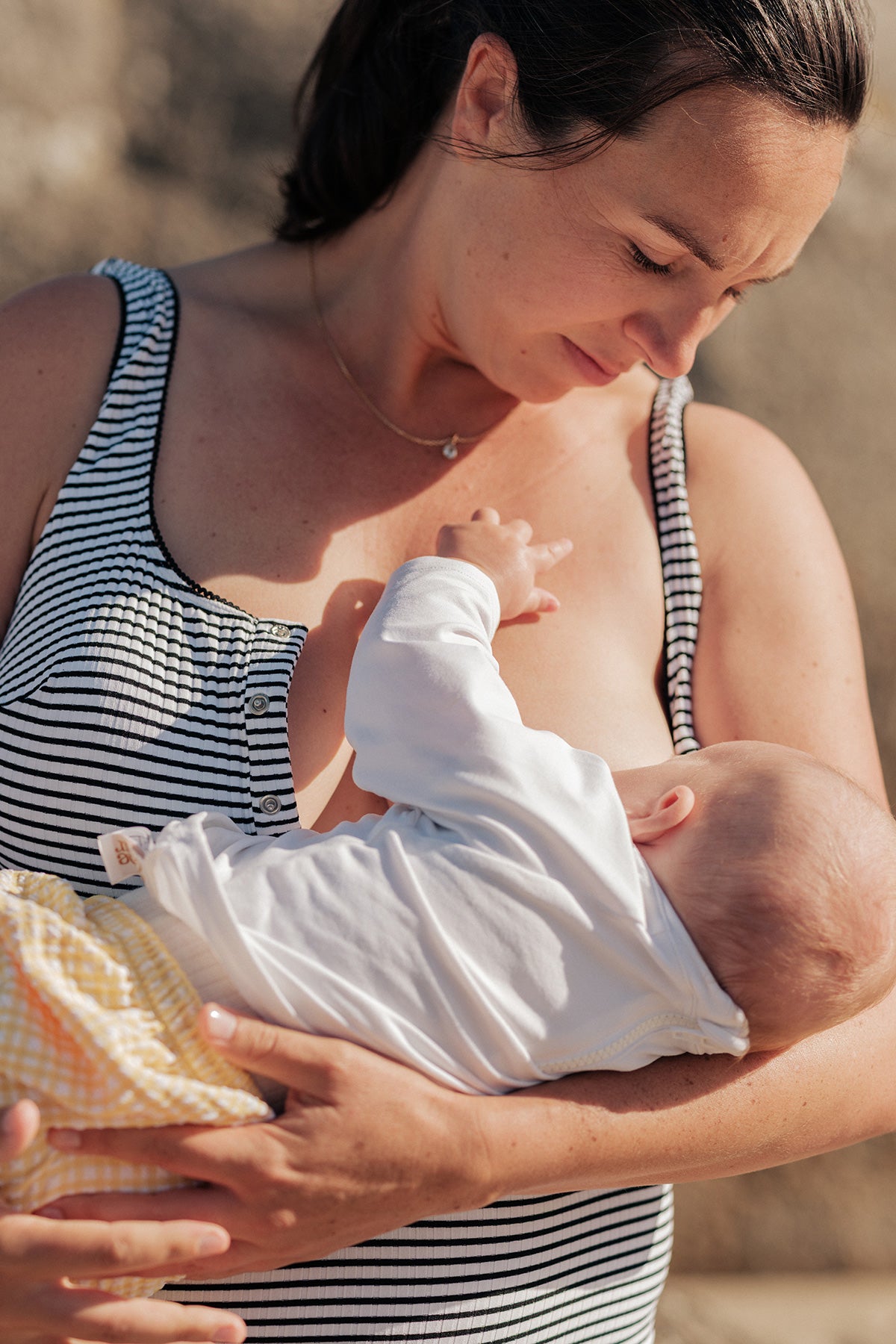 Donna con abito premaman allattamento a righe bianche e nere mentre tiene in braccio un neonato.