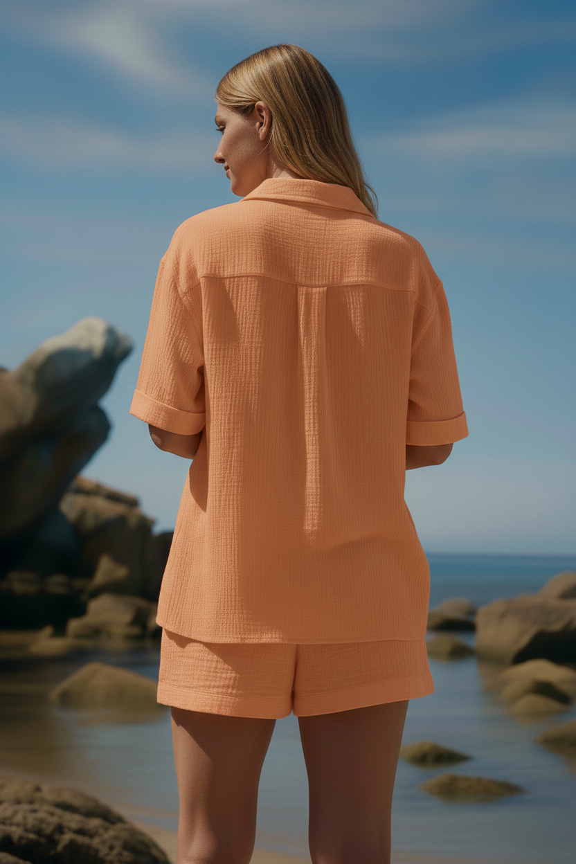 Donna di spalle con completo premaman arancione in tessuto leggero su spiaggia