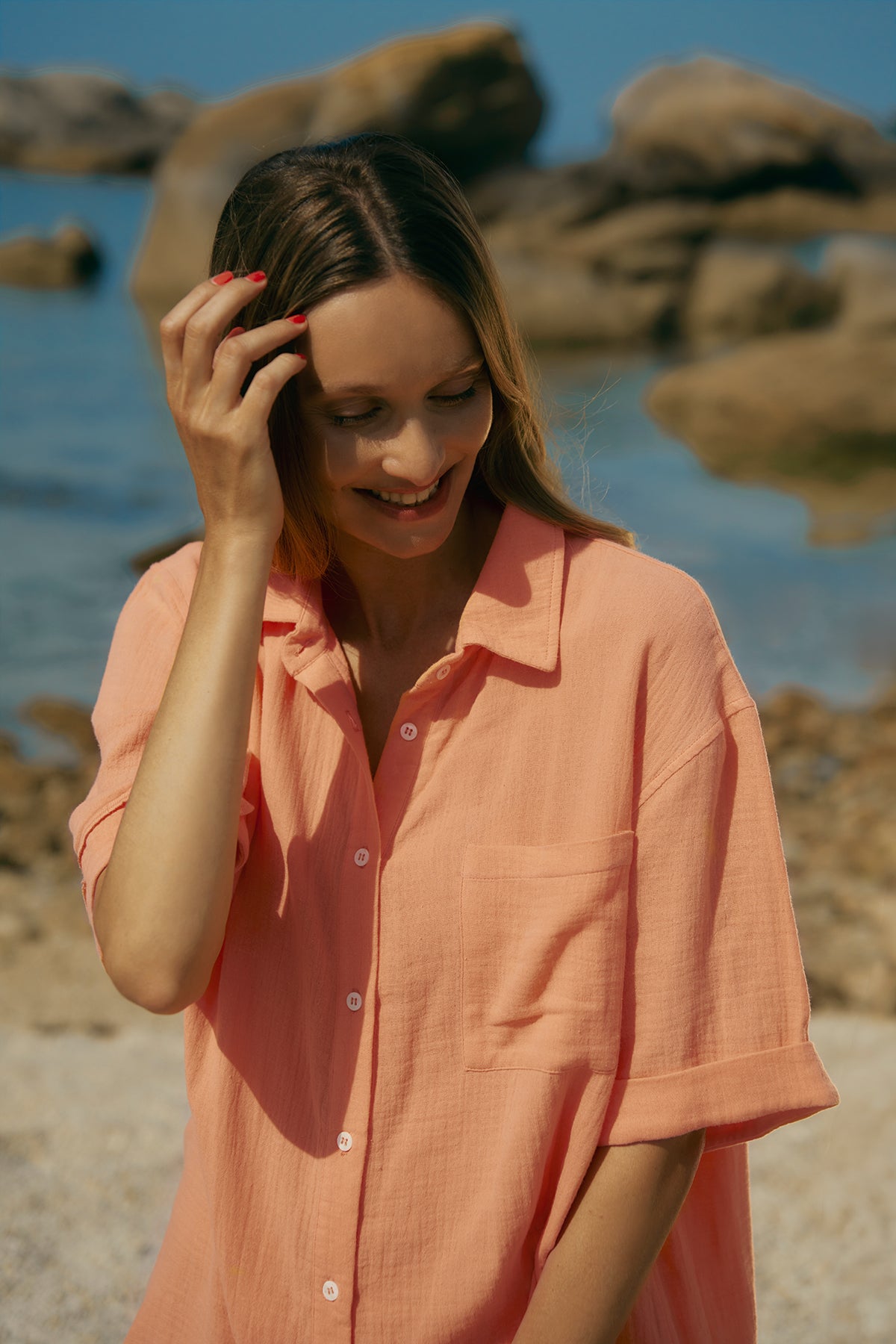 Donna con camicia premaman pesca in cotone, in riva al mare con sfondo roccioso