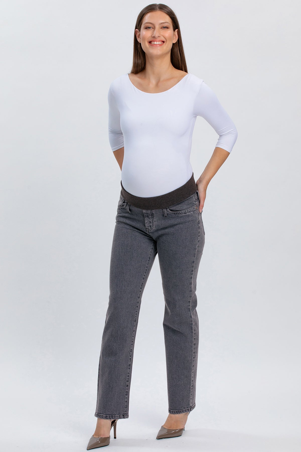 Donna incinta con jeans premaman grigi a gamba dritta e fascia elastica, maglia bianca
