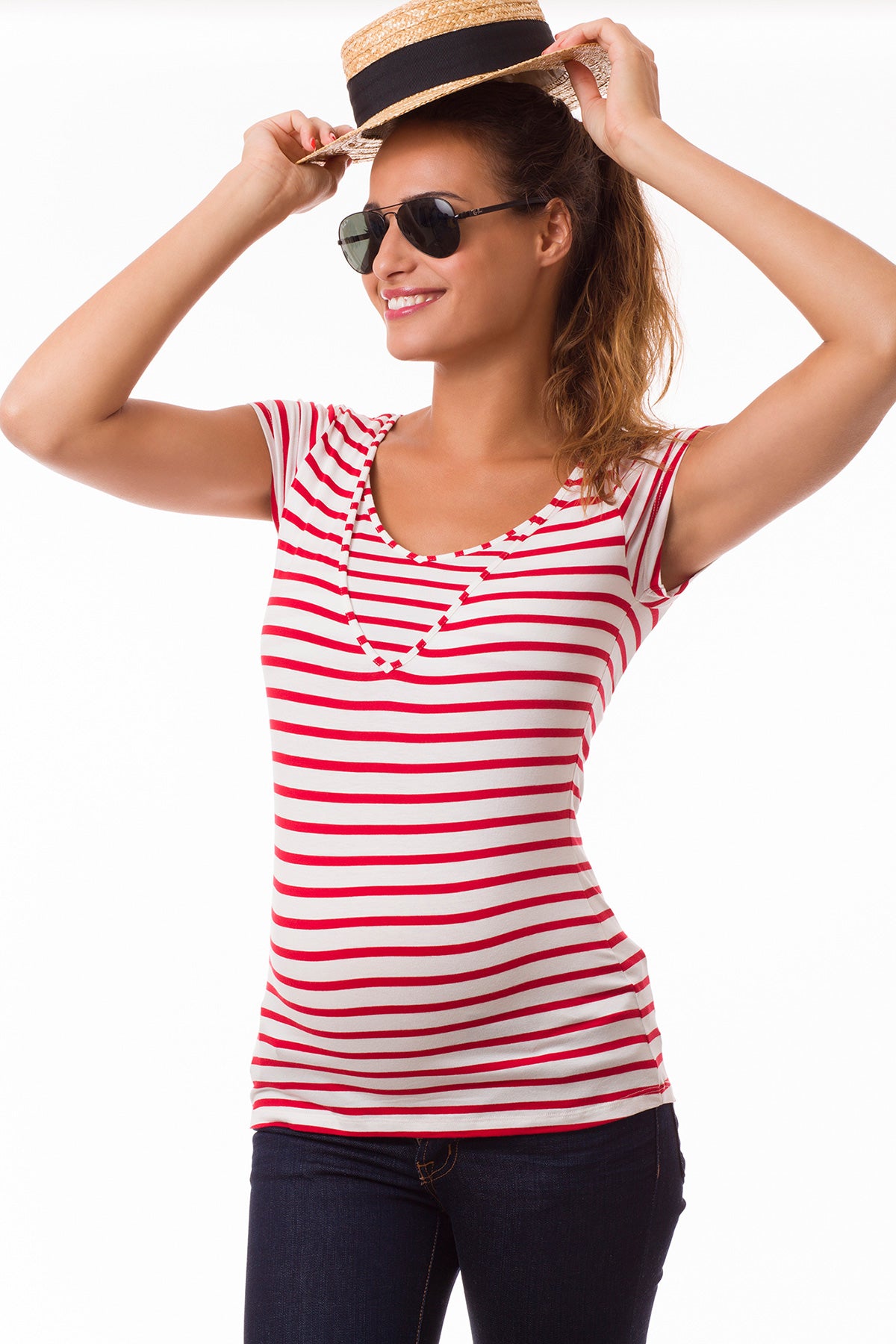 Modella indossa maglietta premaman a righe rosse e bianche, jeans, cappello e occhiali da sole.