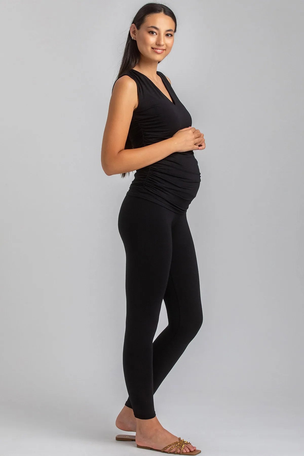 Modella incinta con leggings premaman neri e top smanicato nero, abbigliamento premaman elegante.