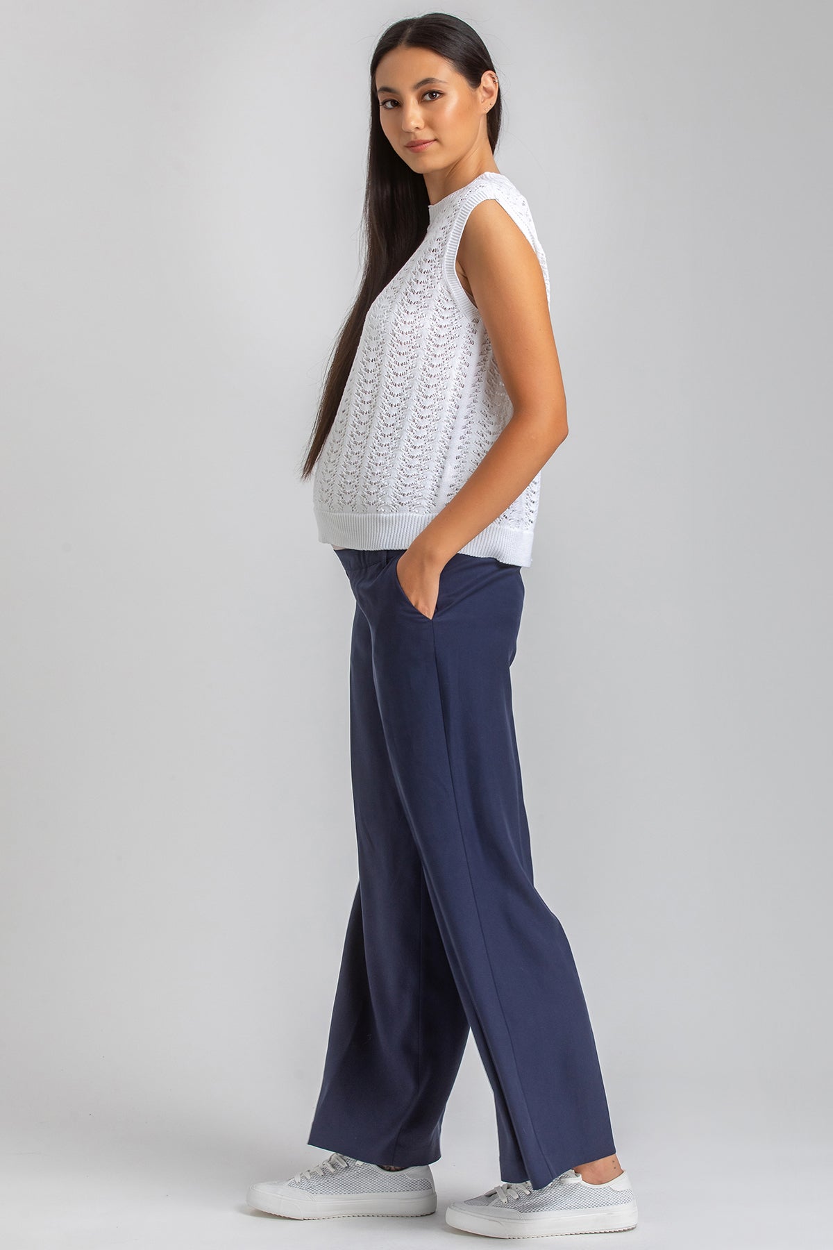 Modella indossa top premaman bianco senza maniche e pantaloni premaman blu larghi