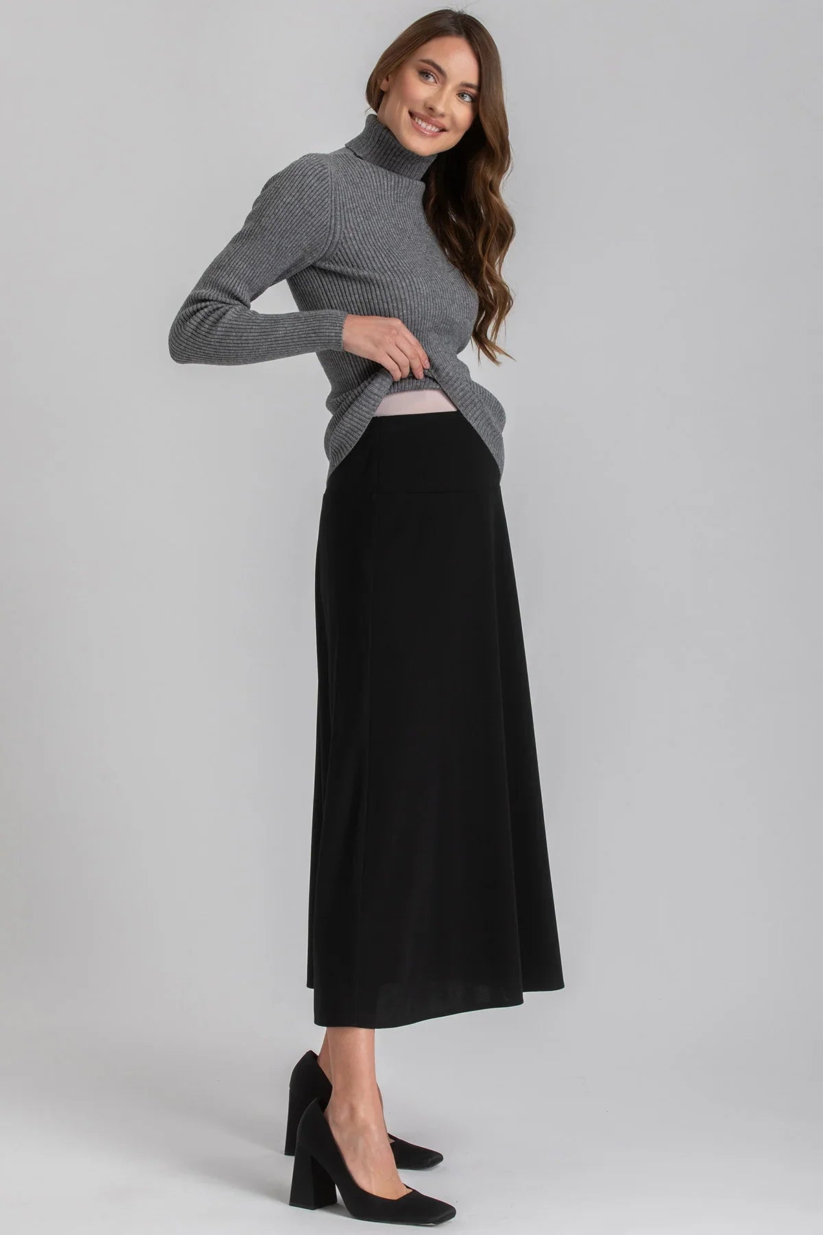 Donna che indossa gonna premaman nera lunga e maglione grigio, abbigliamento premaman elegante