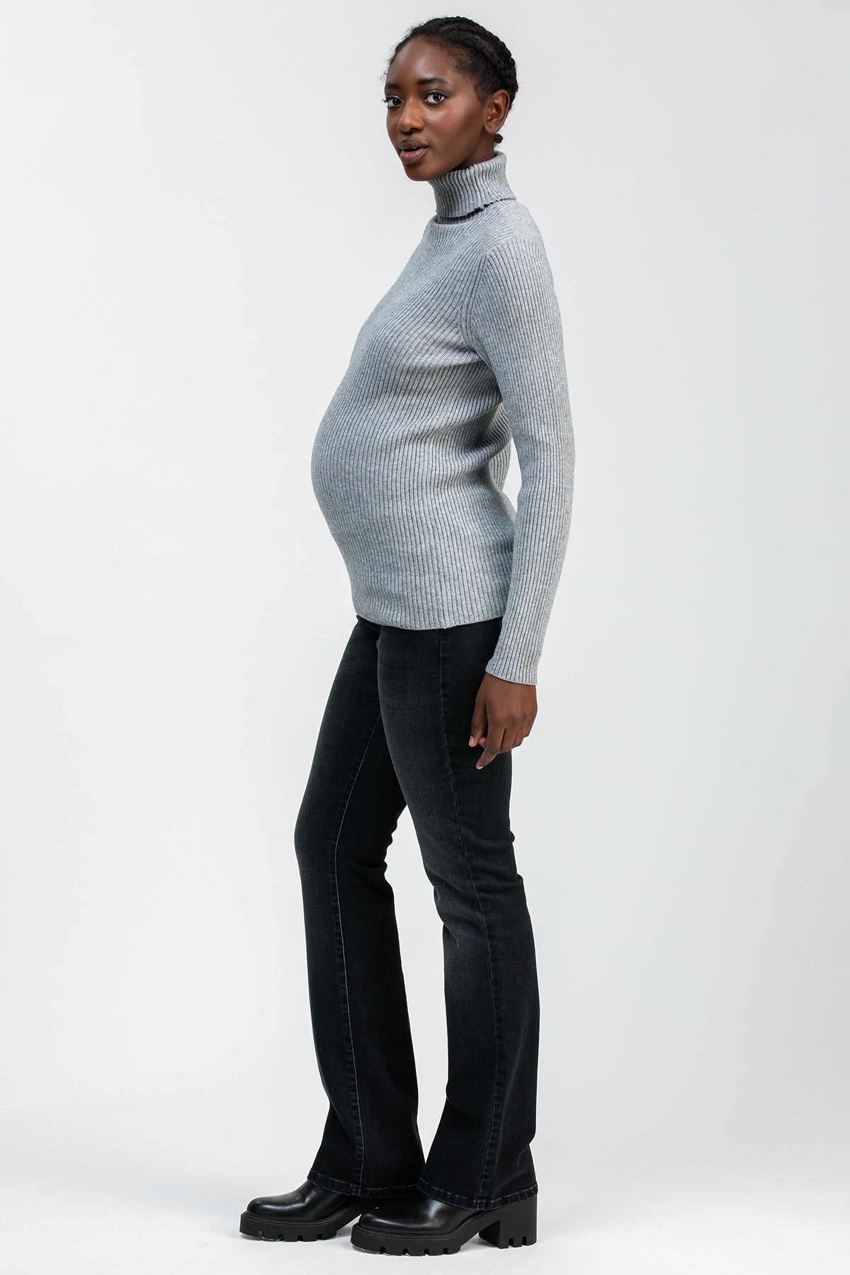 Modella premaman indossa un maglione grigio a collo alto e jeans bootcut neri