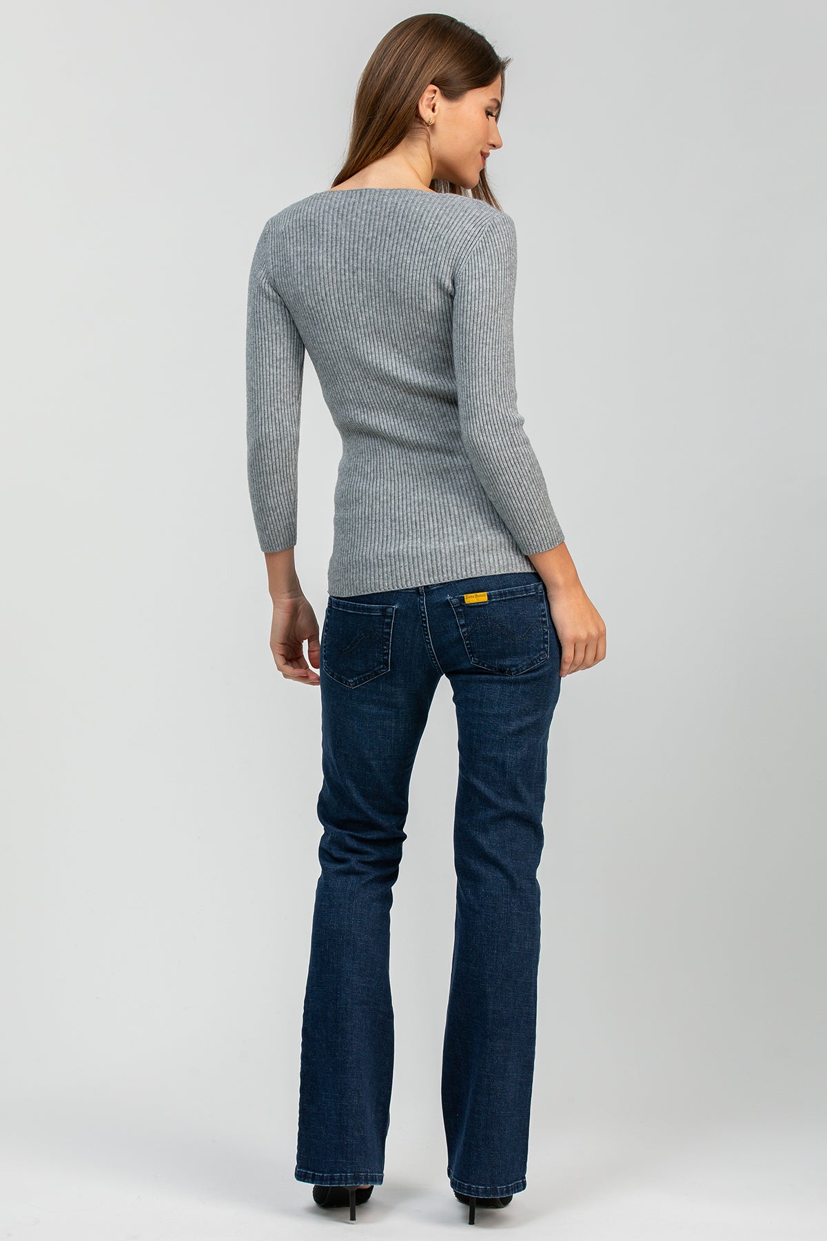 Donna di spalle con maglia grigia a costine e jeans premaman flare blu
